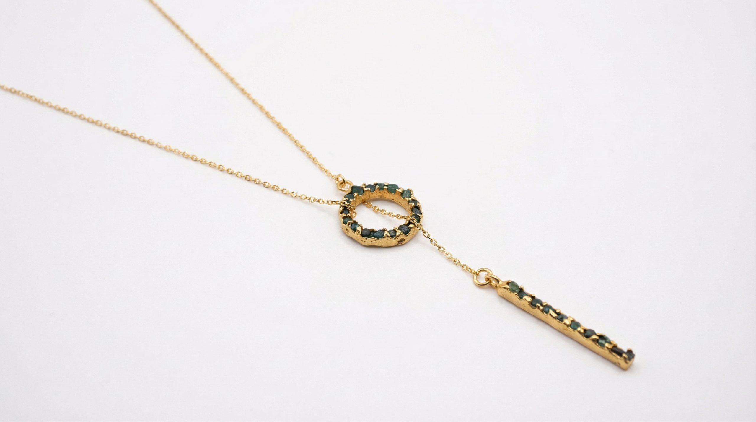 Gold necklace with emerald accents, featuring a circular and bar pendant design, elegant jewelry for women.